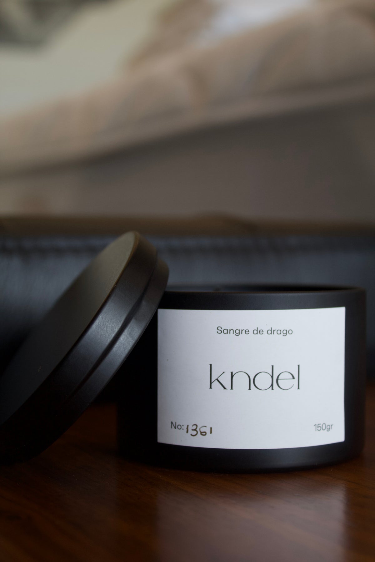 Vela artesanal KNDEL Blaki negra con empaque sobre mesa de madera