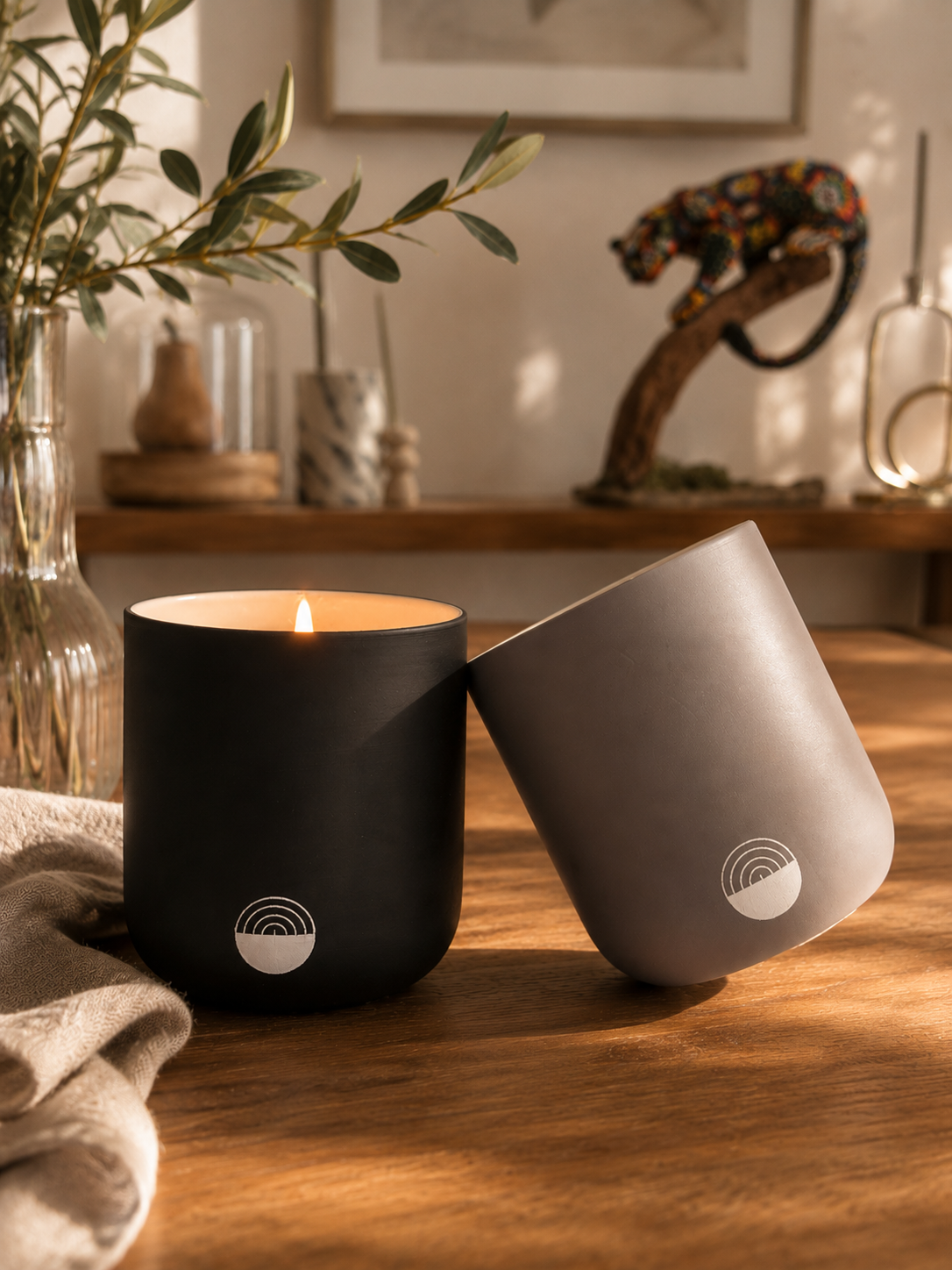Velas artesanales KNDEL negra y gris encendidas sobre mesa de madera
